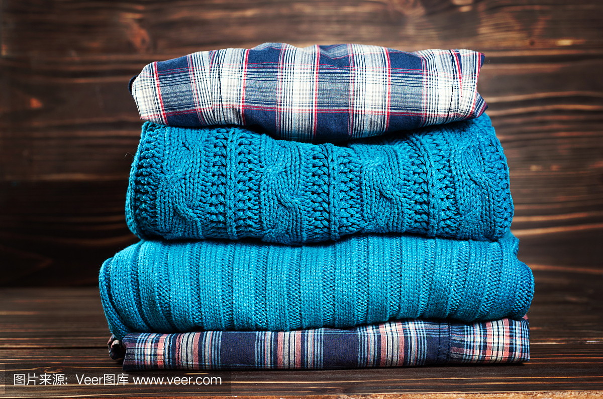 针织羊毛毛衣。成堆的针织冬装、秋装、木质背景、毛衣、针织品。
